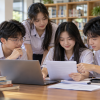 Học sinh cùng xem tài liệu và thông tin kỳ thi trên máy tính, ảnh minh họa